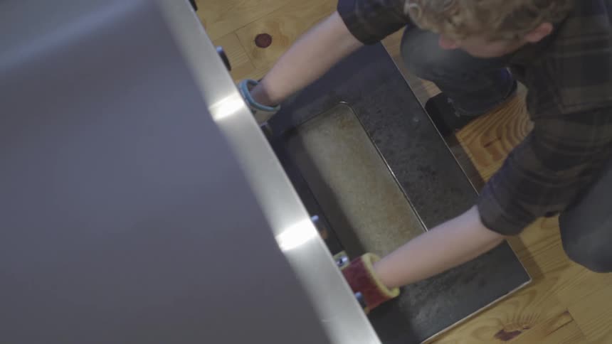 A man opens the oven and takes out a cooked turkey