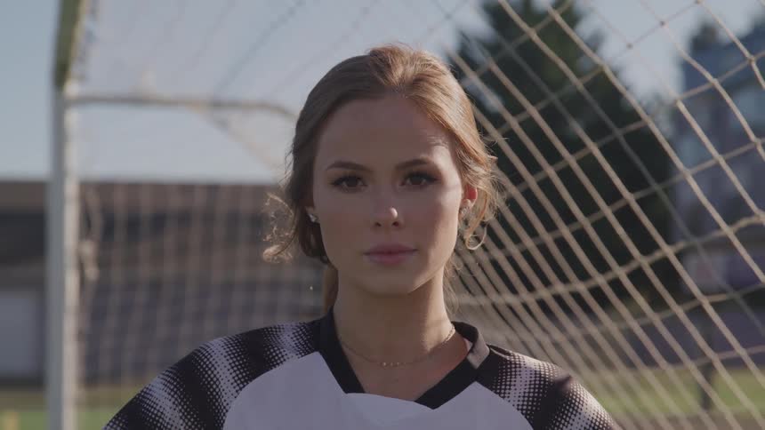 A woman stands in front of a soccer goal on a soccer field