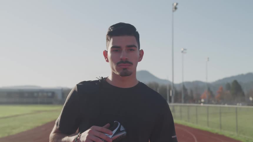 A man stands on a track and field outside