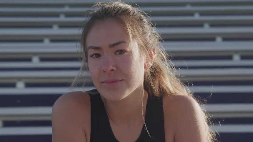 A woman is sitting on the bleachers outdoors