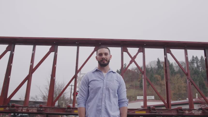 A man standing in front of a train driving down the tracks