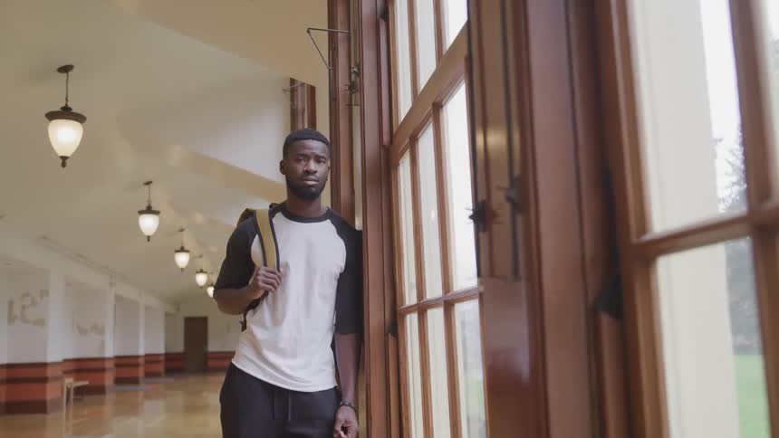 A man is standing inside a building while wearing a backpack