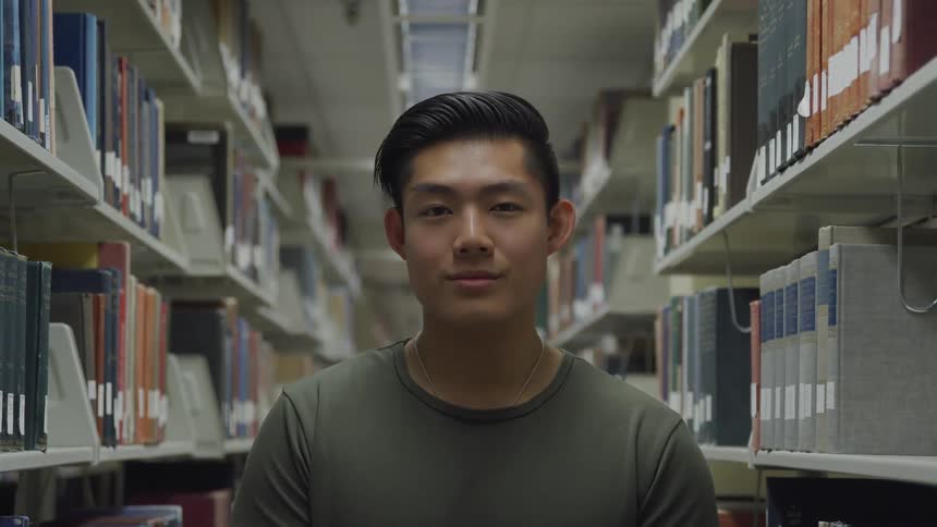 Man standing next to library shelves smiles