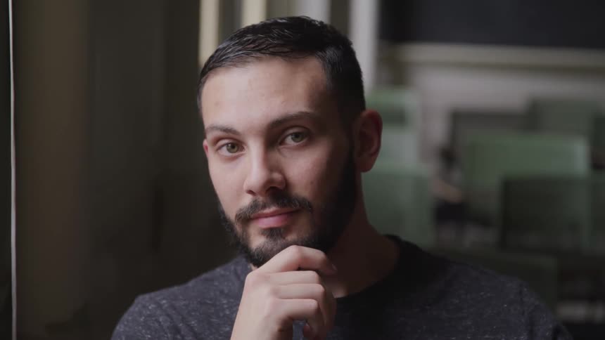 Close up of a young man face sitting in a room looking at the camera