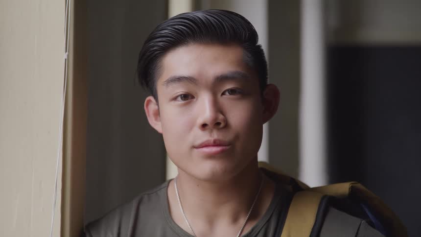 A man is standing in a building and wearing a backpack