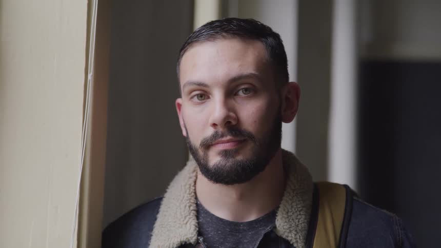 A man is standing in a building while wearing a jacket
