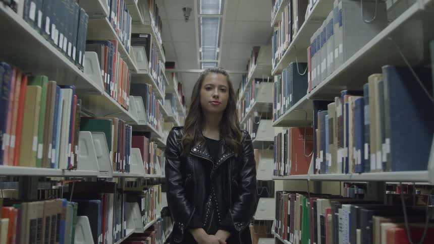 Young woman wearing black leather jacket standing on the library