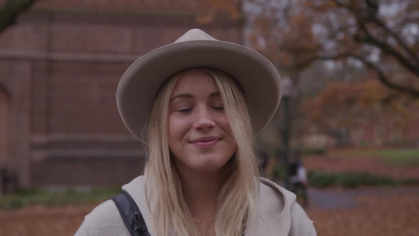 Young woman on college campus turns and smiles at camera