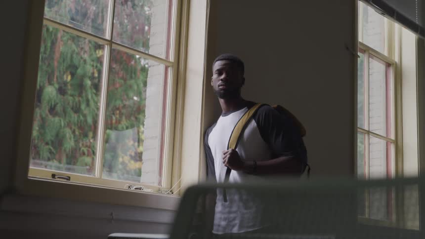A man is standing in a room while looking out a window