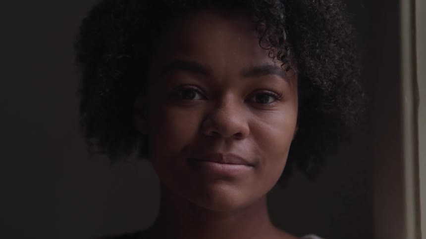 A woman is standing in a room and is smiling