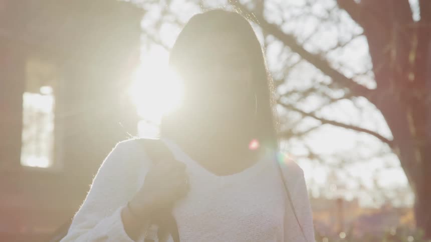 Young woman standing outdoors looks at the camera at sunset