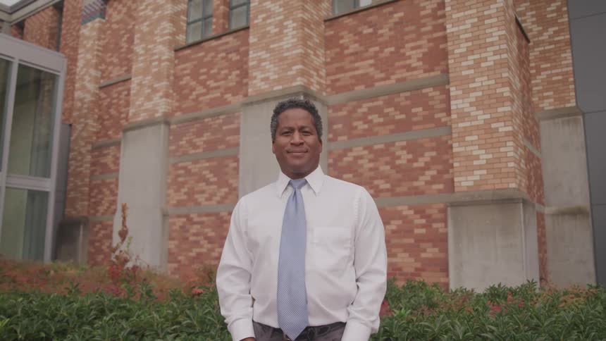 A man is standing outdoors and smiling