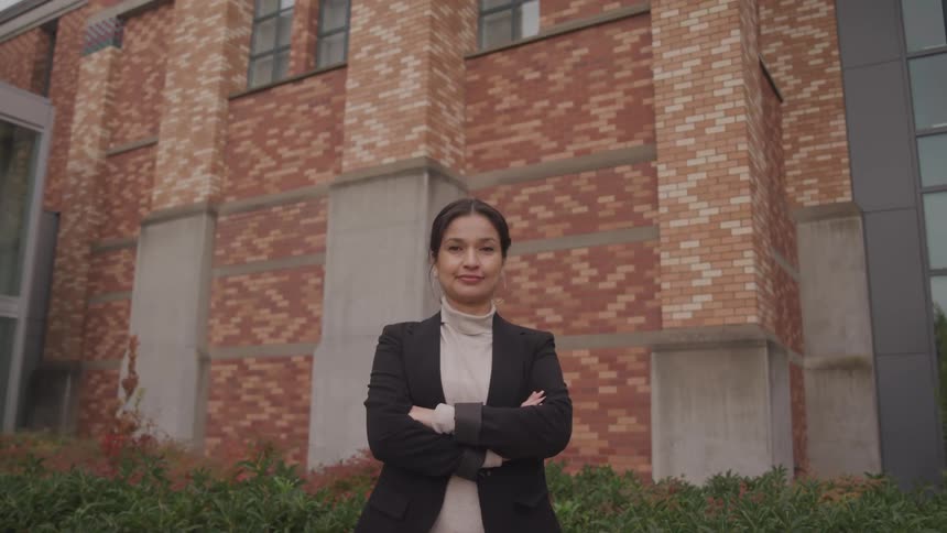 A female standing out wearing a suit coat and smiling