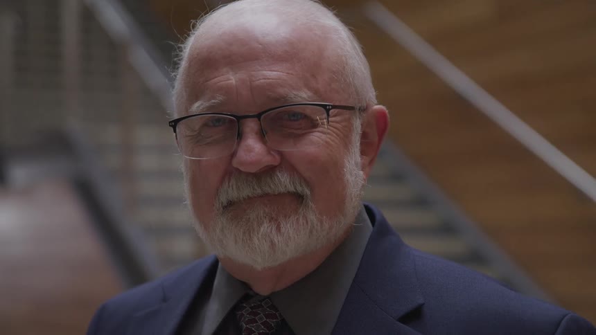 An elderly man standing in front of a set of stairs