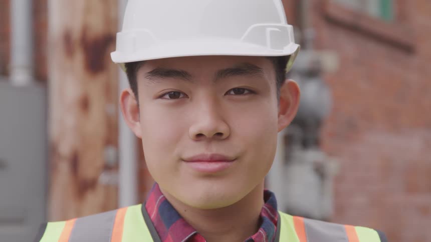 A construction worker is standing outside of a building