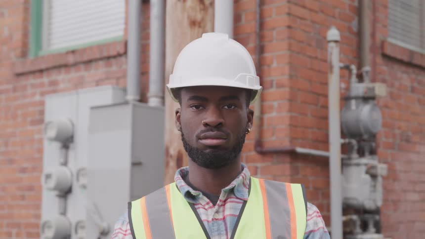 A construction worker is standing outdoors in a city