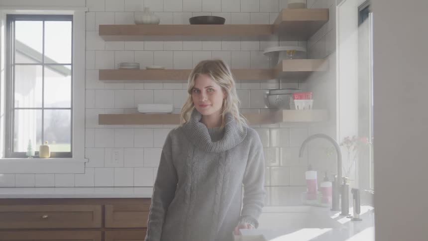 A woman stands in her home kitchen by the sink