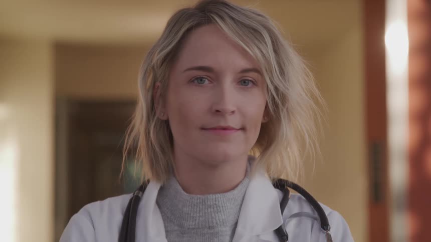 Doctor wearing lab coat and stethoscope turns around to look at the camera