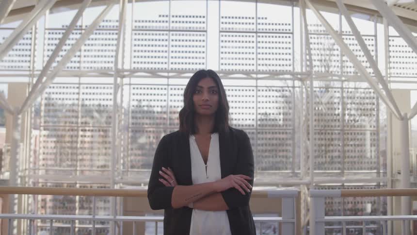Person stands in front of rail near window showing city