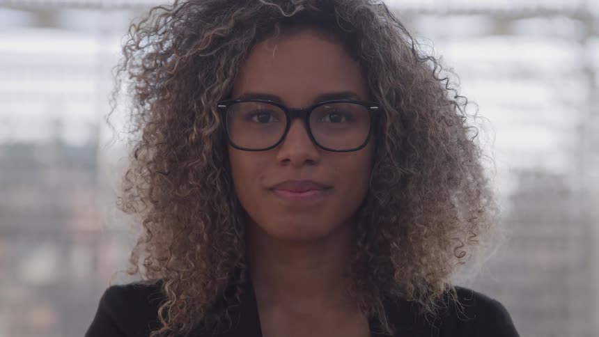 Young woman wearing glasses turns around to look at the camera