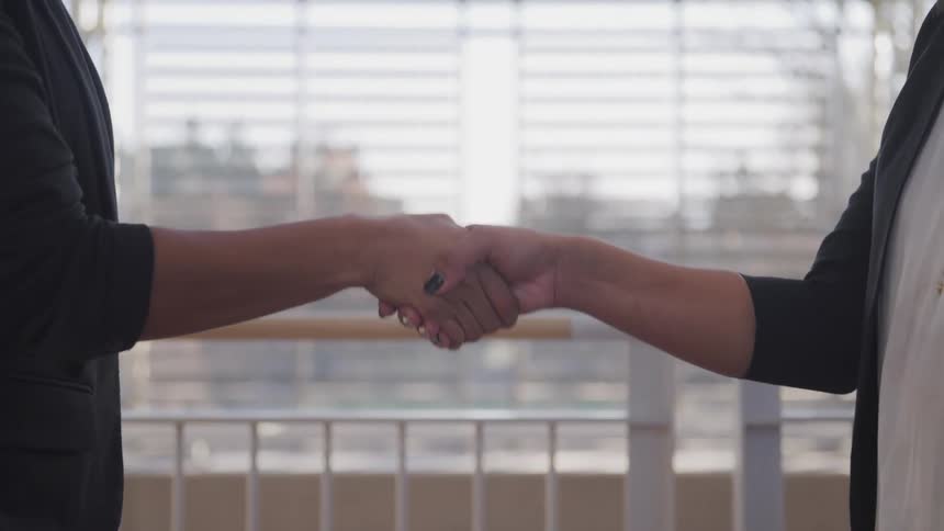 Two women extend their hands to each other in order to shake hands