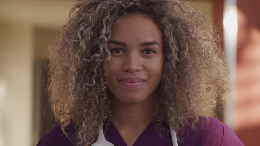 A young woman with a stethoscope around her neck turns and smiles