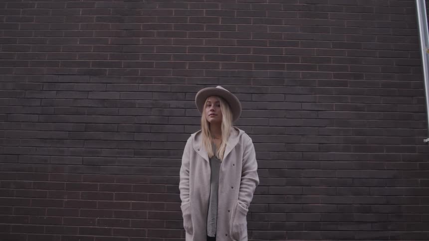 A woman is standing outdoors in a city while wearing a coat