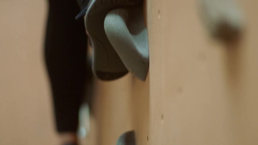 Person uses its feet to help climb an indoor climbing wall