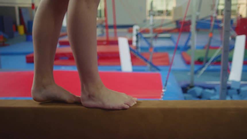 A young girl walking on a balance beam as she practices gymnastics