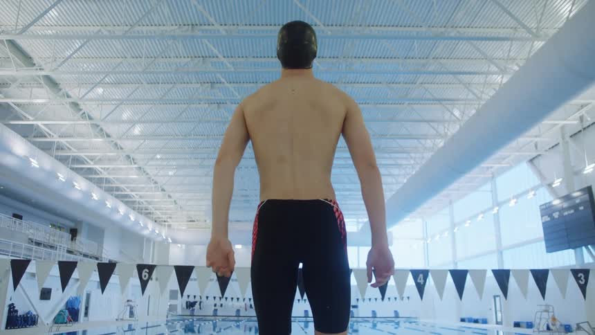 A man with a swimming cap on his head standing by a pool