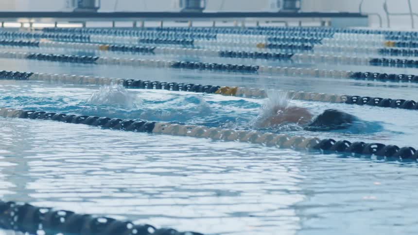 A person swimming in olympic size swimming pool with water