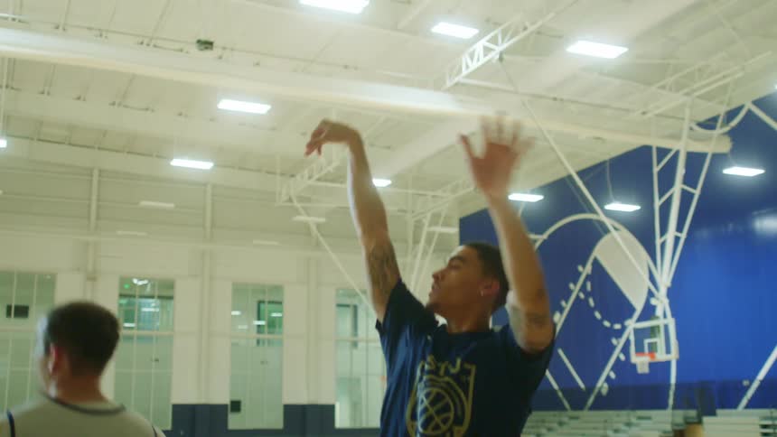 A man takes a shot at the net with a basketball at an indoor court
