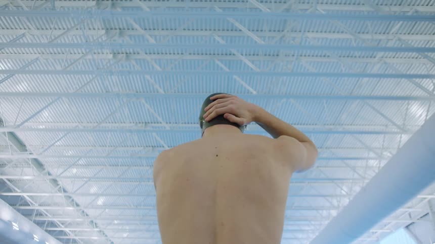 A man adjusting a swimming cap on his head with his hands
