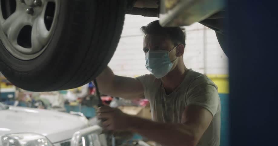 Mechanic tightening lug nuts on car tire in shop