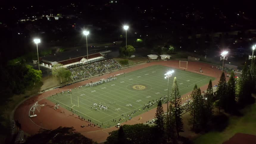 An aerial view of people watching a football game at night