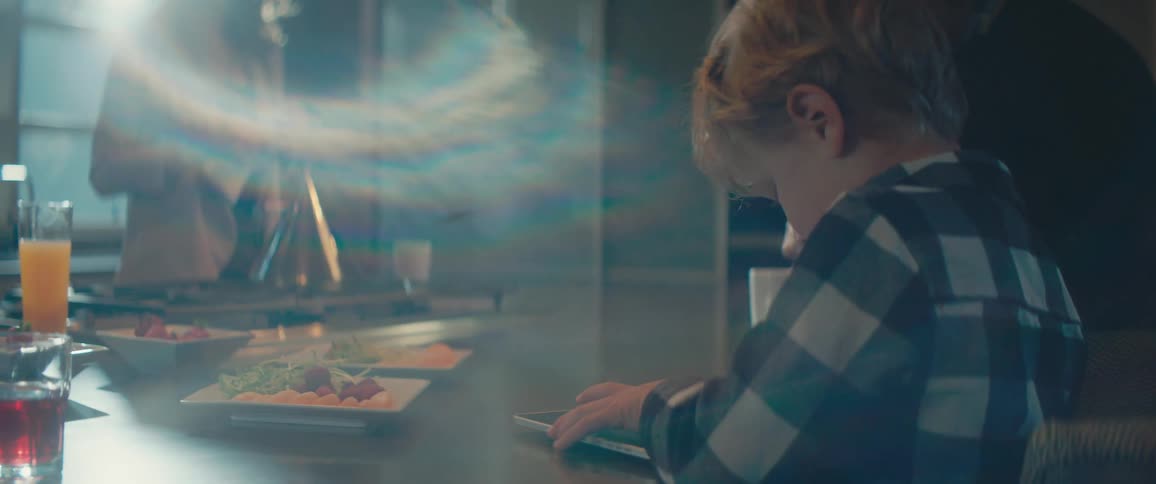 A young boy sits at a kitchen counter with different foods on the counter