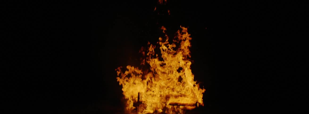 Rising orange flames on a bonfire at night