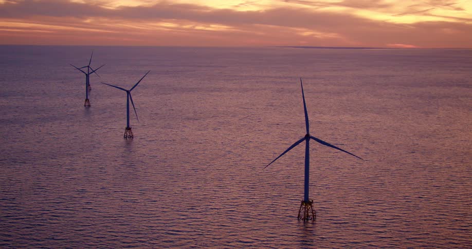 Wind turbines in ocean in front of sunset
