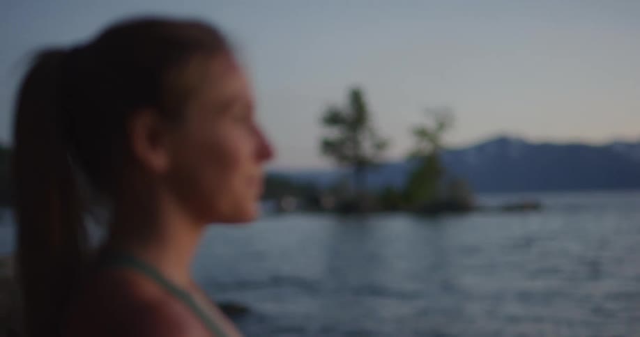 A woman is standing outdoors by the ocean