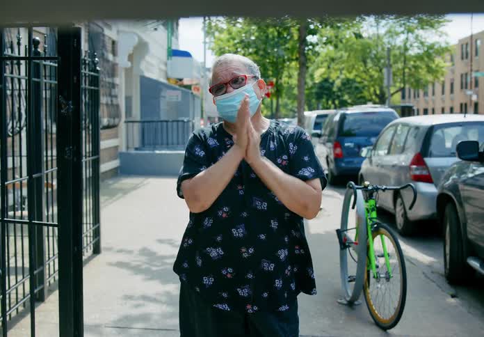 Woman wearing face mask clapping outdoors on sidewalk
