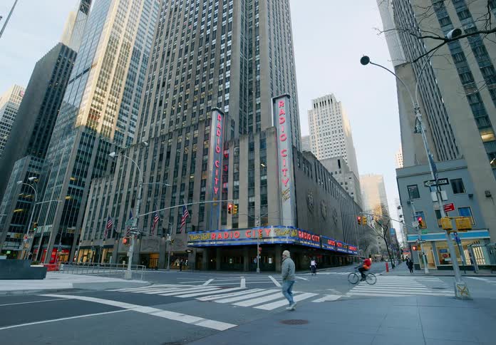 A man walks across a city intersection and then stops in the middle of the road