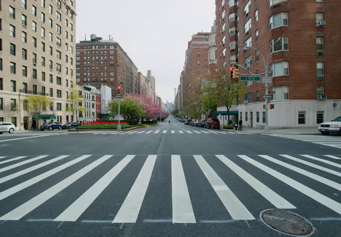 Pedestrians walk toward intersection with red stop light