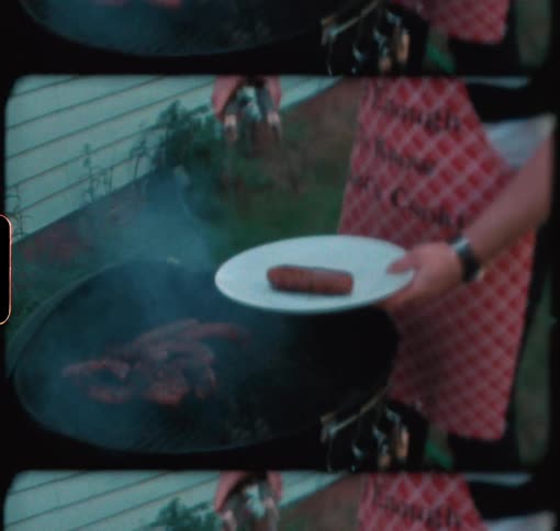A man grills hot dogs on a charcoal grill in the summertime