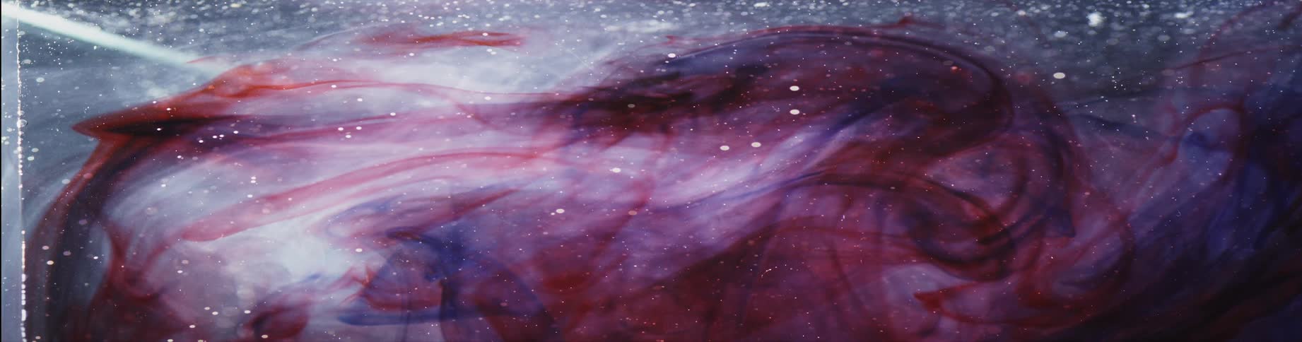 Colorful swirls float over black and white background dotted with twinkling particles