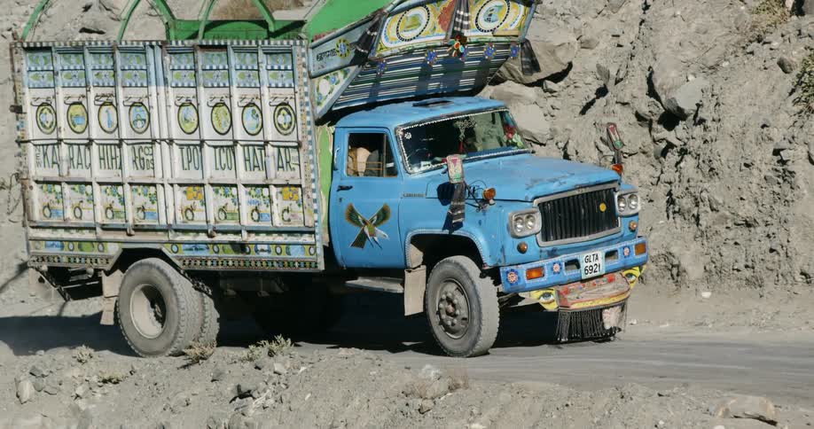 A shipping truck slowly drives along a road