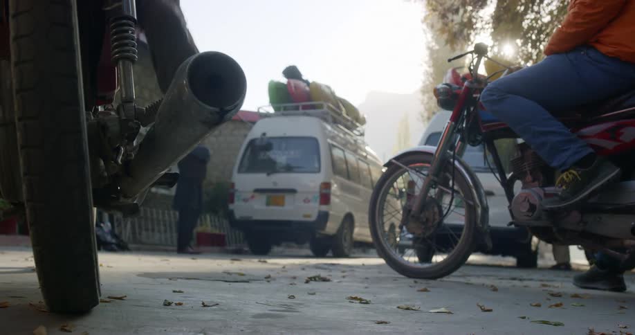Two men start motorcycles and drive forward