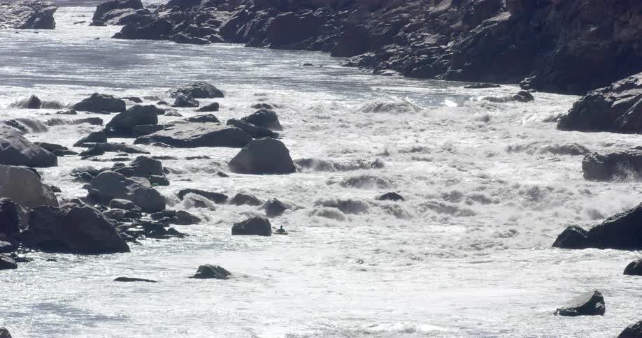 Two people kayaking through river rapids
