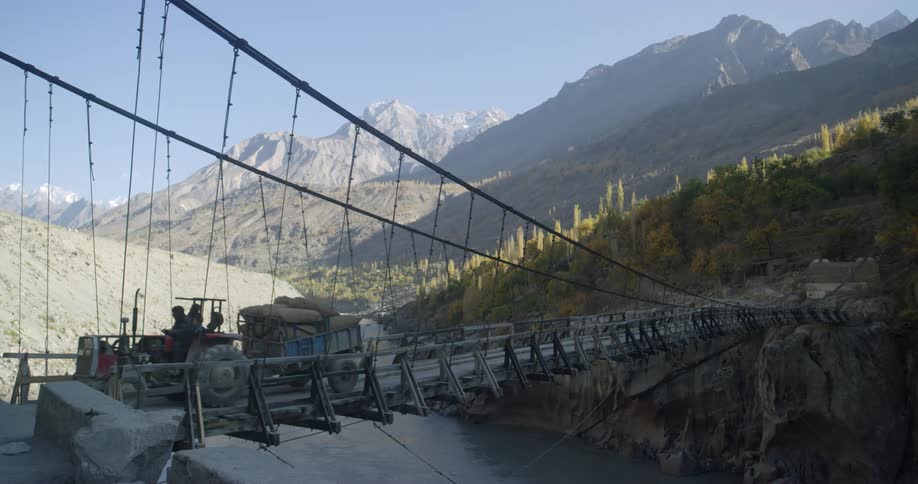 A small tractor is pulling some cargo across the bridge