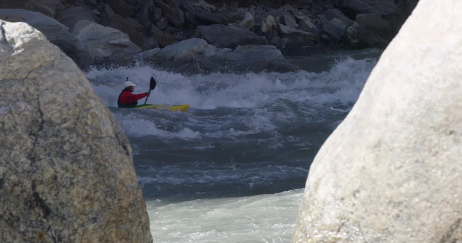 A kayaker paddles down river through the rapids of a river