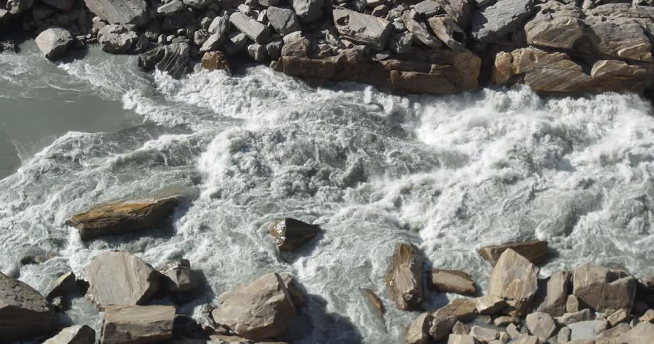 The rapids of a river rushing between large stones on either side of the river
